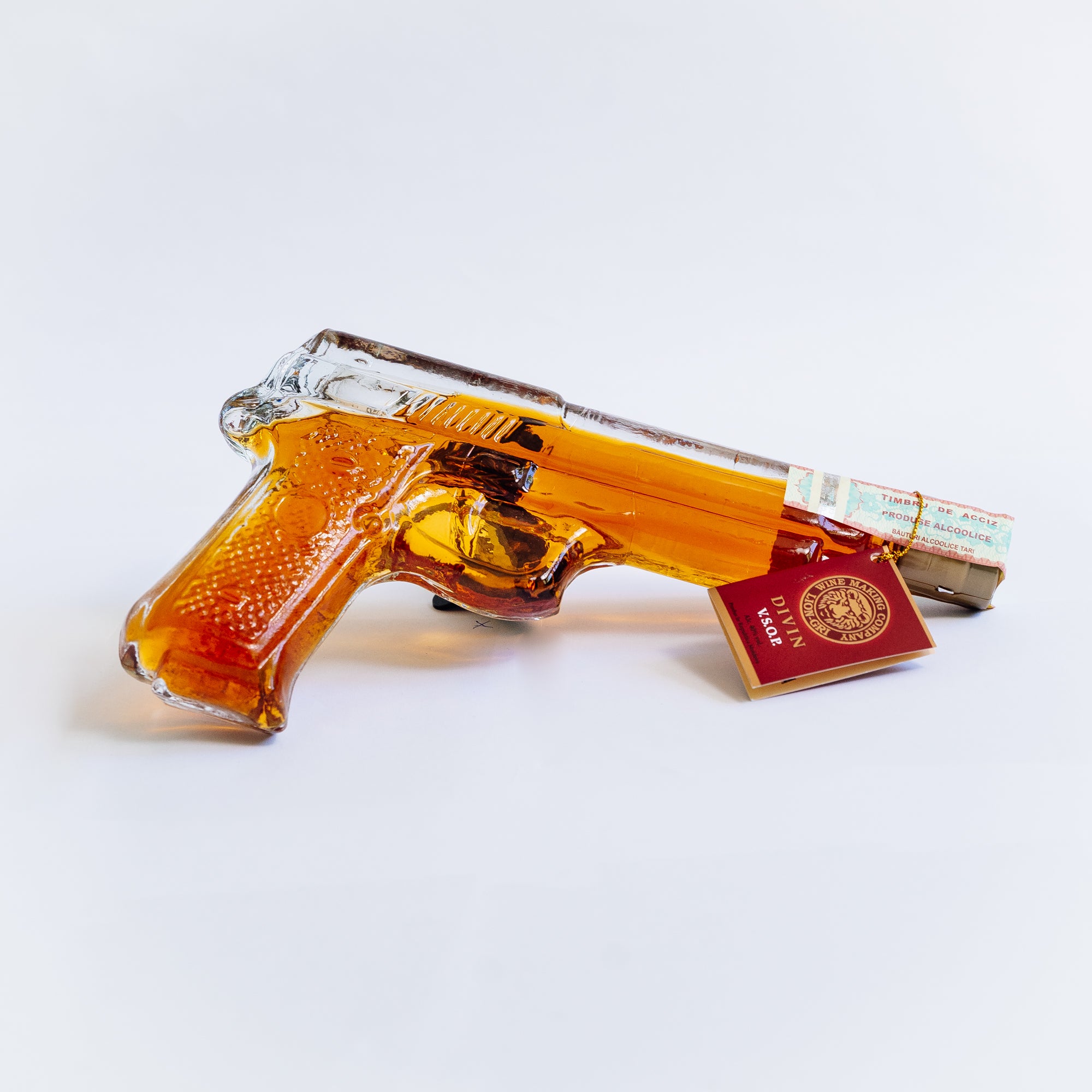Sticlă decorativă Divin VSOP Pistol Bereta Lion-gri, transparentă cu lichid ambră.